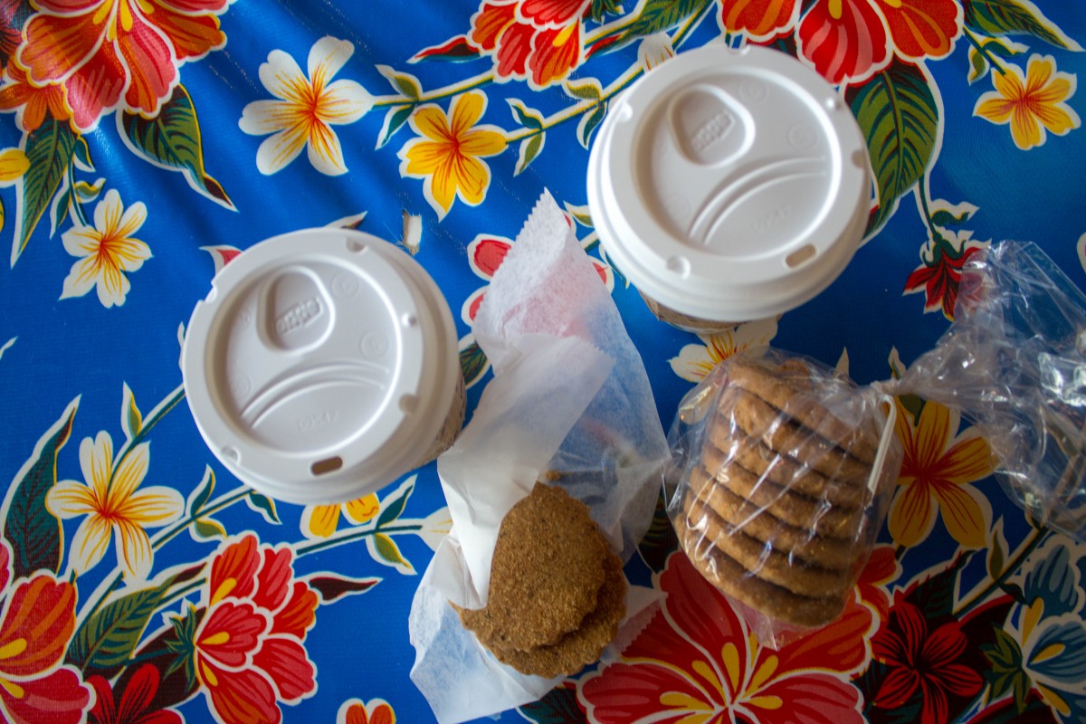 a packet of biscochitos and two cups of coffee on a colorful floral placemat. 