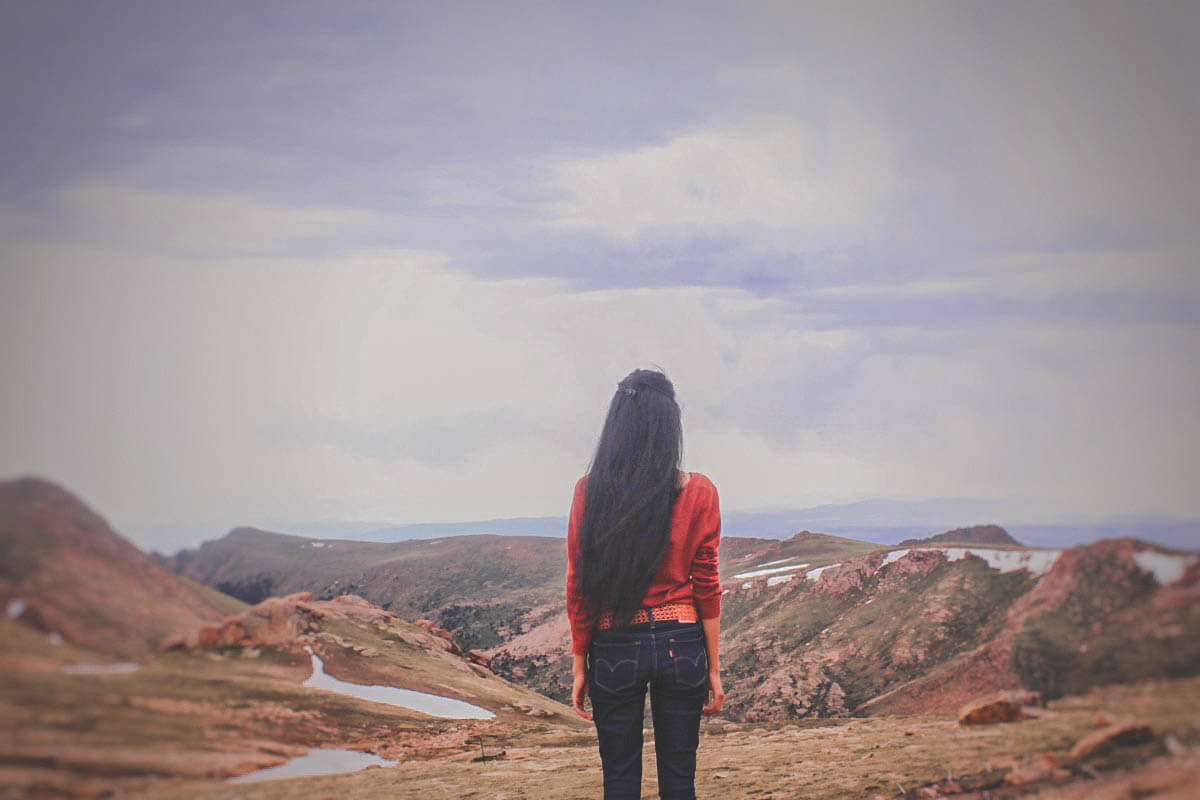 Girl standing on top of mountain with little pools of water in front of her