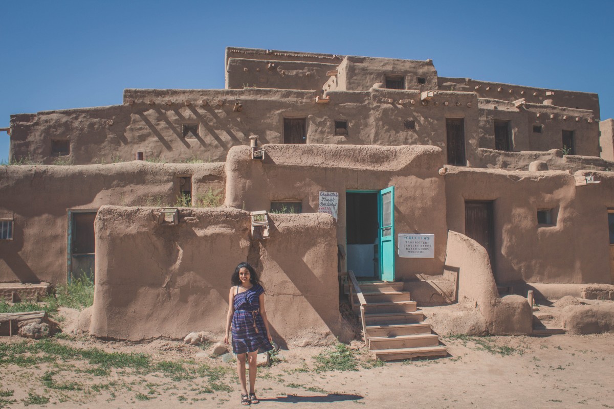Anshula standing in front of the adobe of Taos Pueblo in Taos