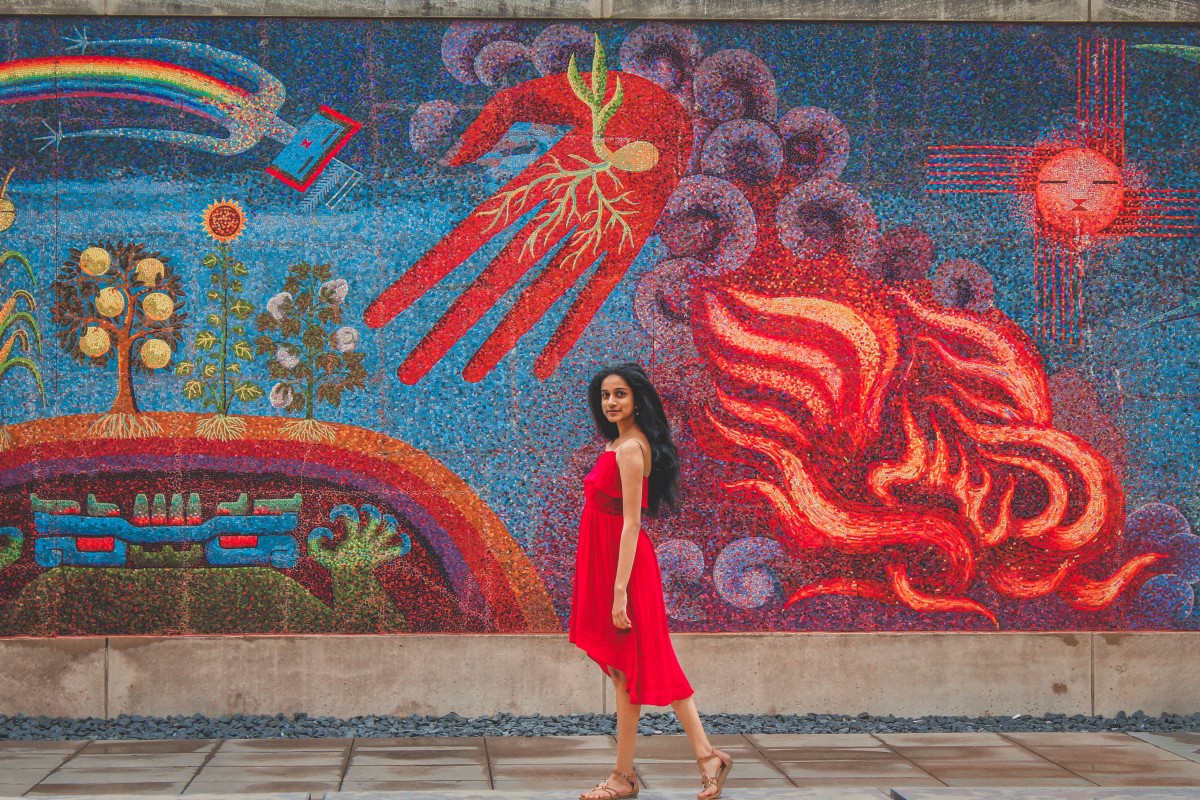 girl in red dress standing in front of a bright colorful mural outside of the DMA, located in the Dallas Arts District