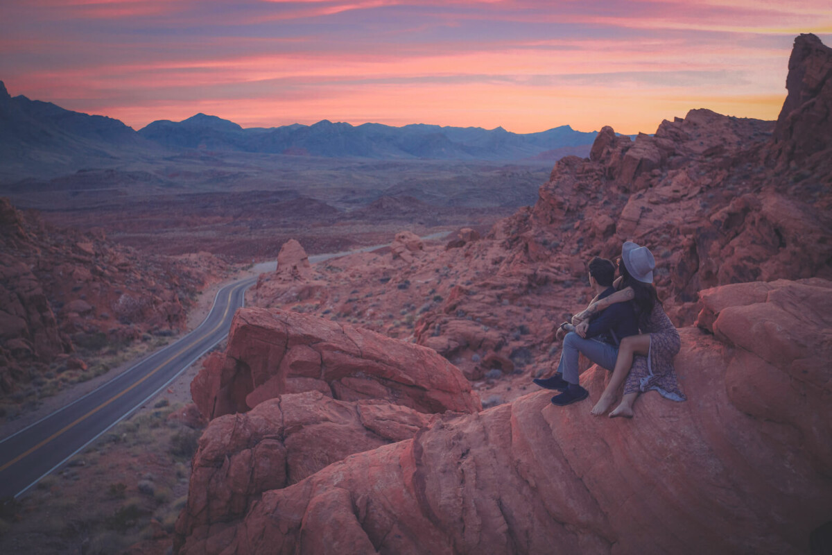 couple hugging atop a sloping cliff to represent adventure road trip questions for couples