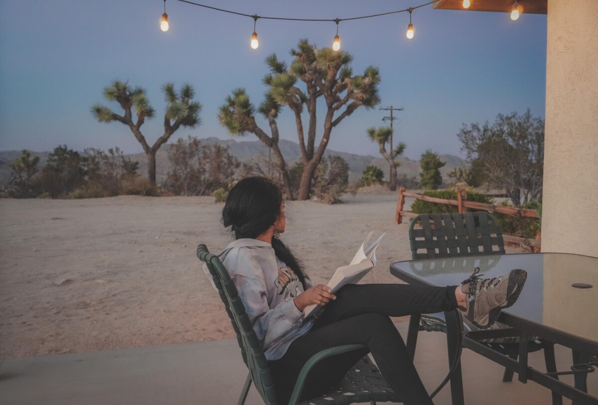 day trip to Joshua Tree : image of Airbnb in Joshua Tree in the evening with twinkle lights and girl reading a book in Joshua Tree
