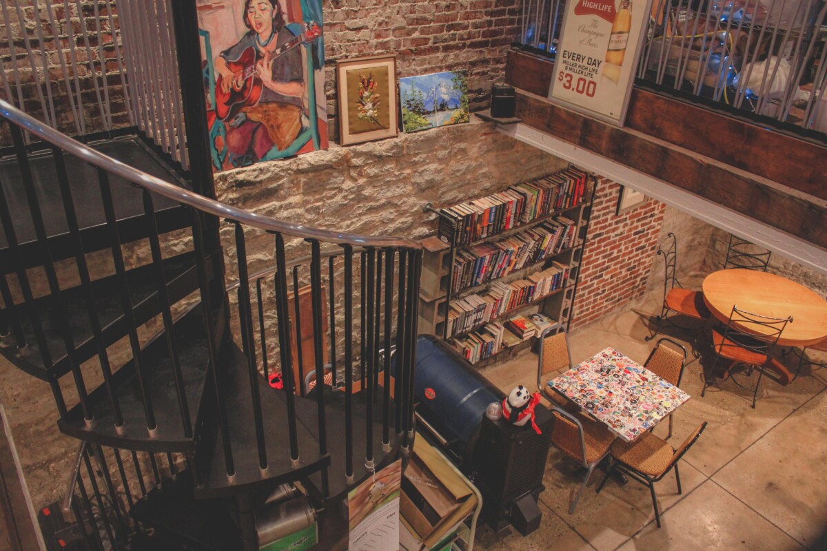 Porter Books And Bread lower level with wall art, staircase, cafe seating, and bookcase