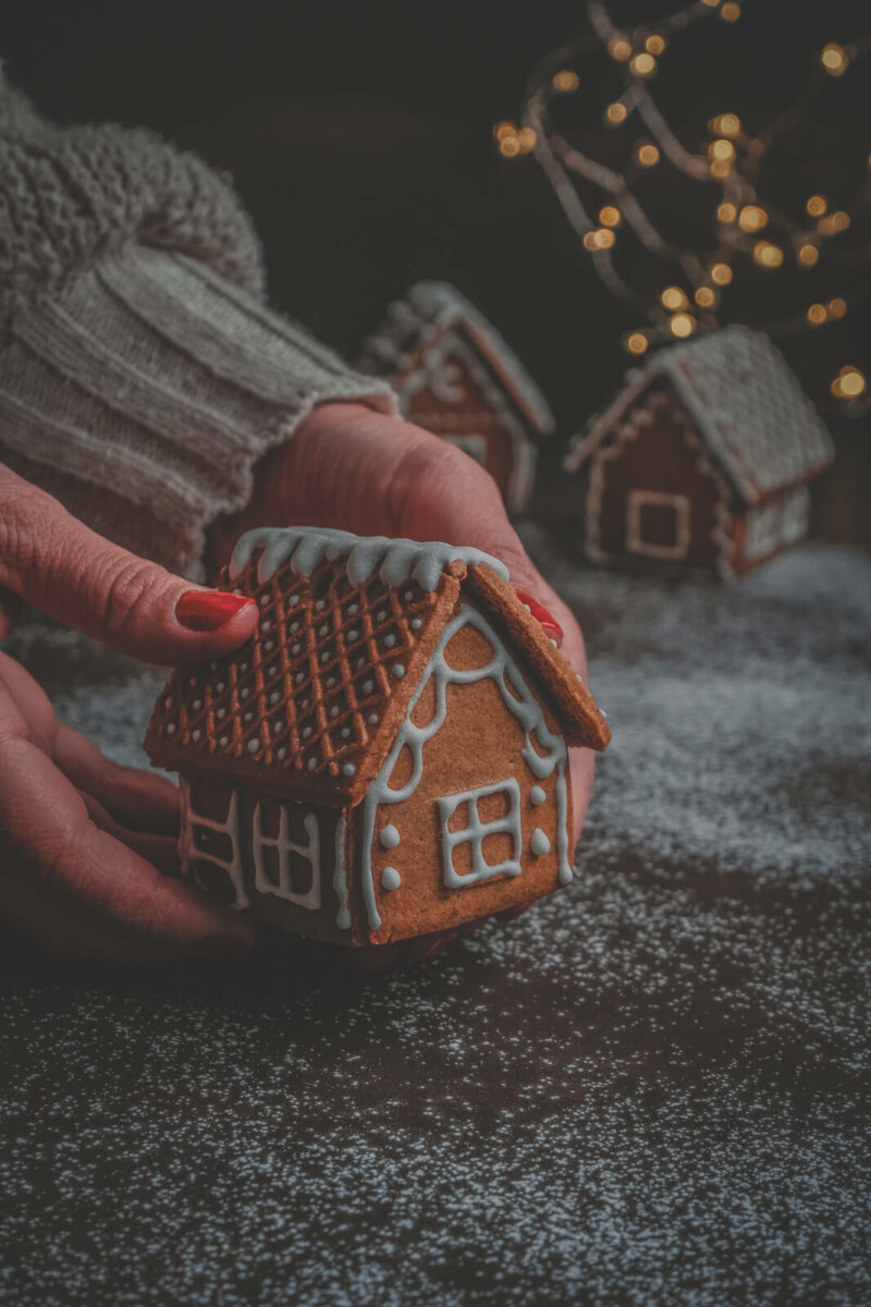 a woman holding a gingerbread house to represent the author, Tina Casalino, growing up in a home in a holiday town 