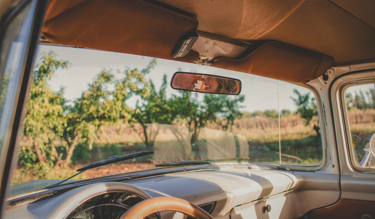 couple being cute in the rear view mirror to represent intimate road trip questions for couples