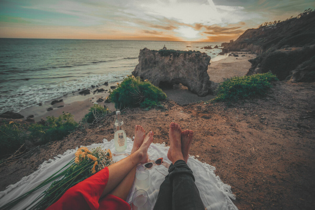 a couple sipping lemonade near the coast while on a road trip break