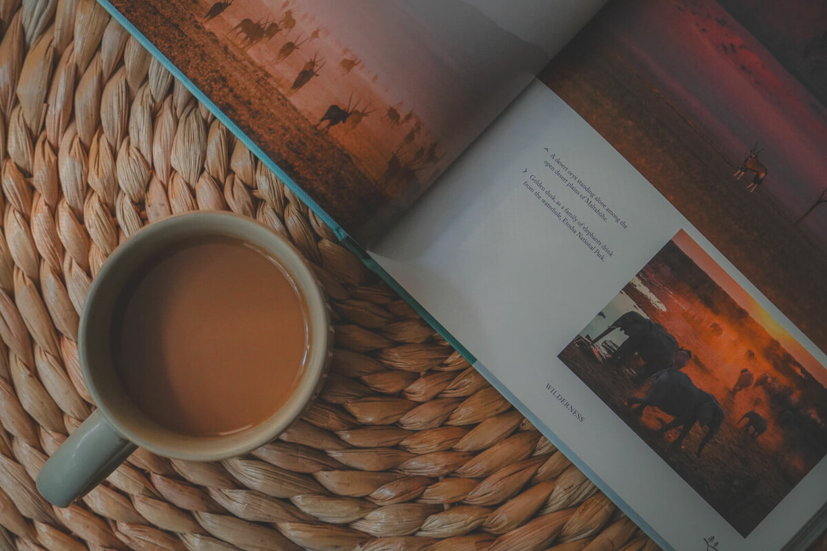 photo of a mug of coffee and a flipped open copy of Let's Get Lost, one of the best coffee table books for travel lovers