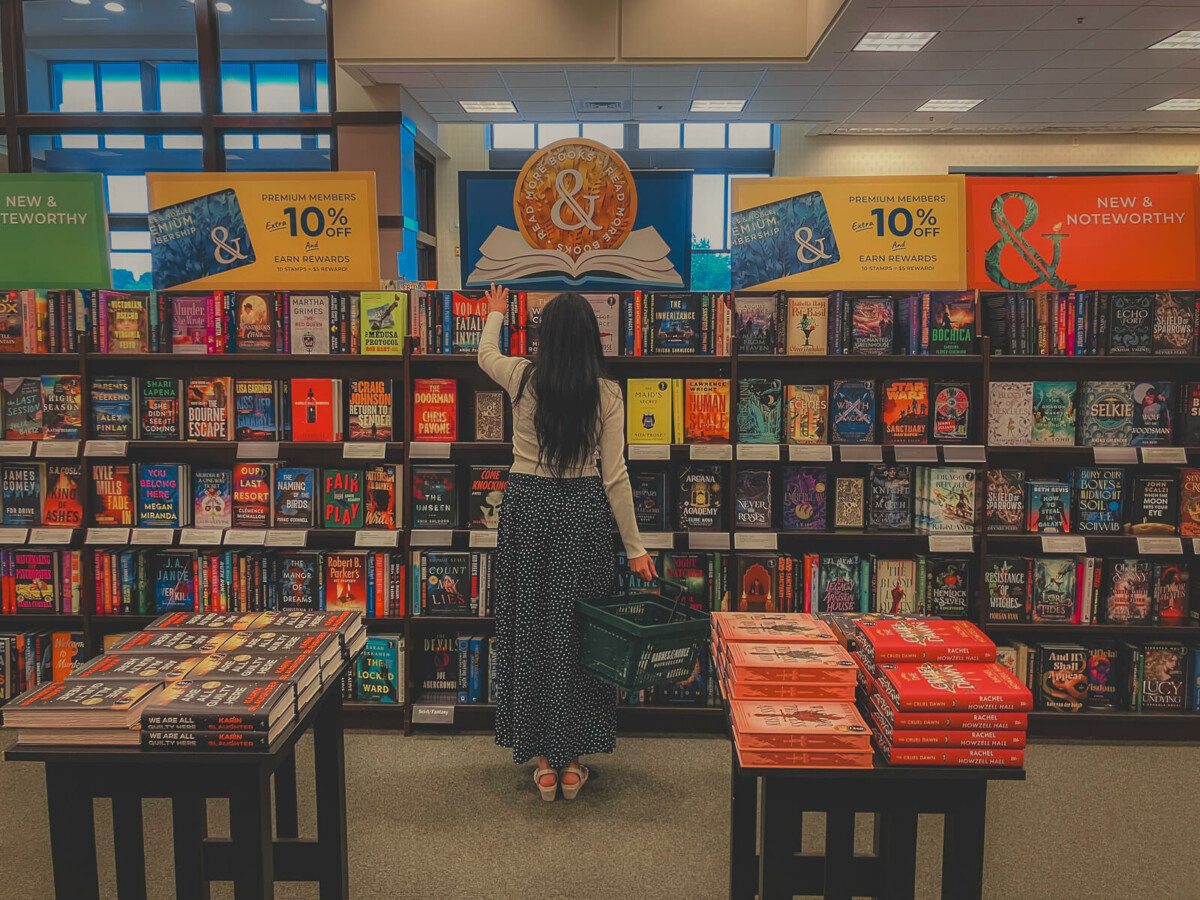 a woman browses through Barnes & Noble in front of a Barnes & Noble membership sign