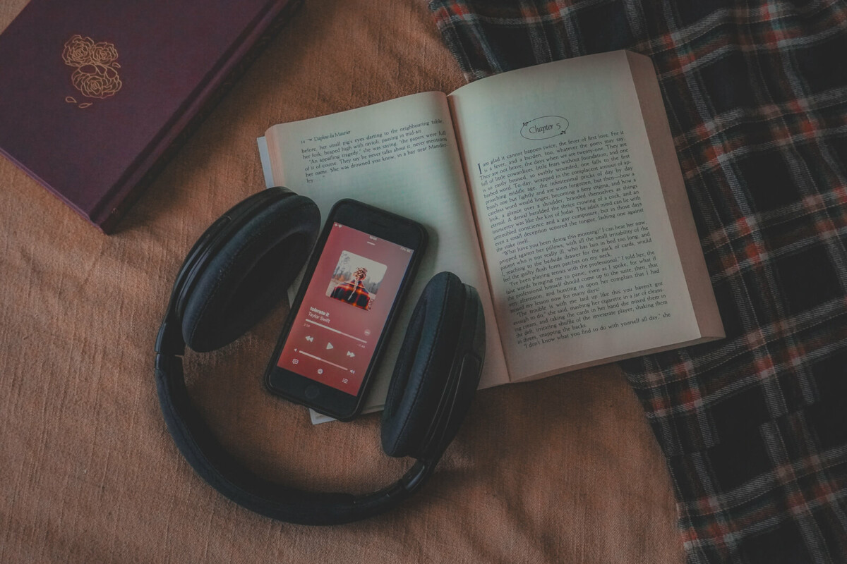 flatlay photo featuring a copy of Rebecca by Daphne du Maurier (the book referenced in the song Tolerate It), a plaid oversized shirt, and a hardback copy of one of the best books to read in autumn