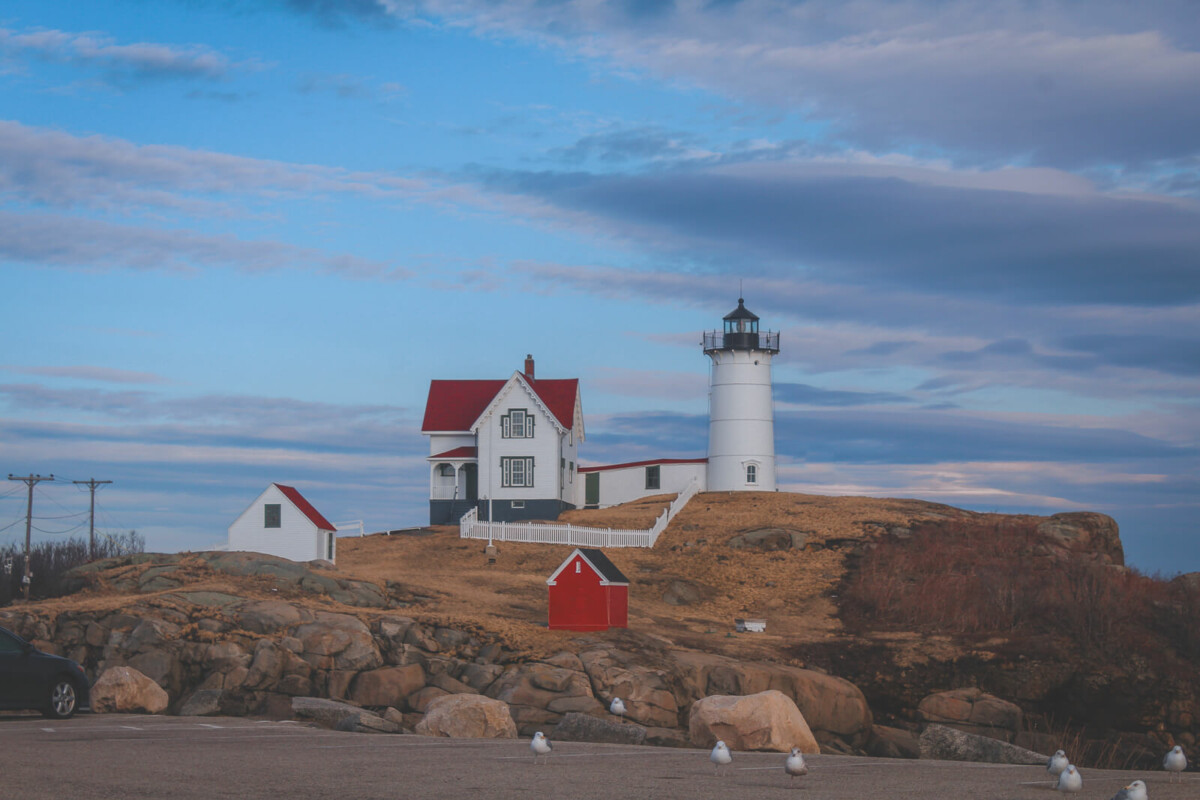 a picturesque lighthouse on the coast of Maine, one of the best states to travel to for a charming coastal road trip