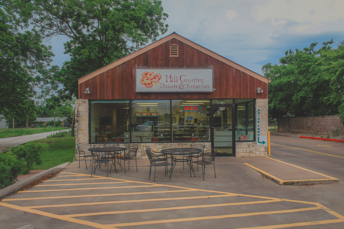 a smal town donut shop titled Hill Country Donuts and Kolaches amongst cottagecore scenery in Hill Country, Texas