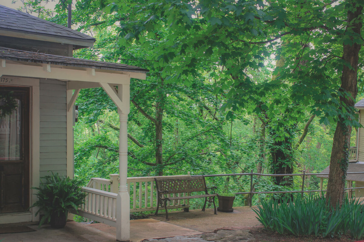 a bench for two in front of the lush green landscape of a forested mountain town